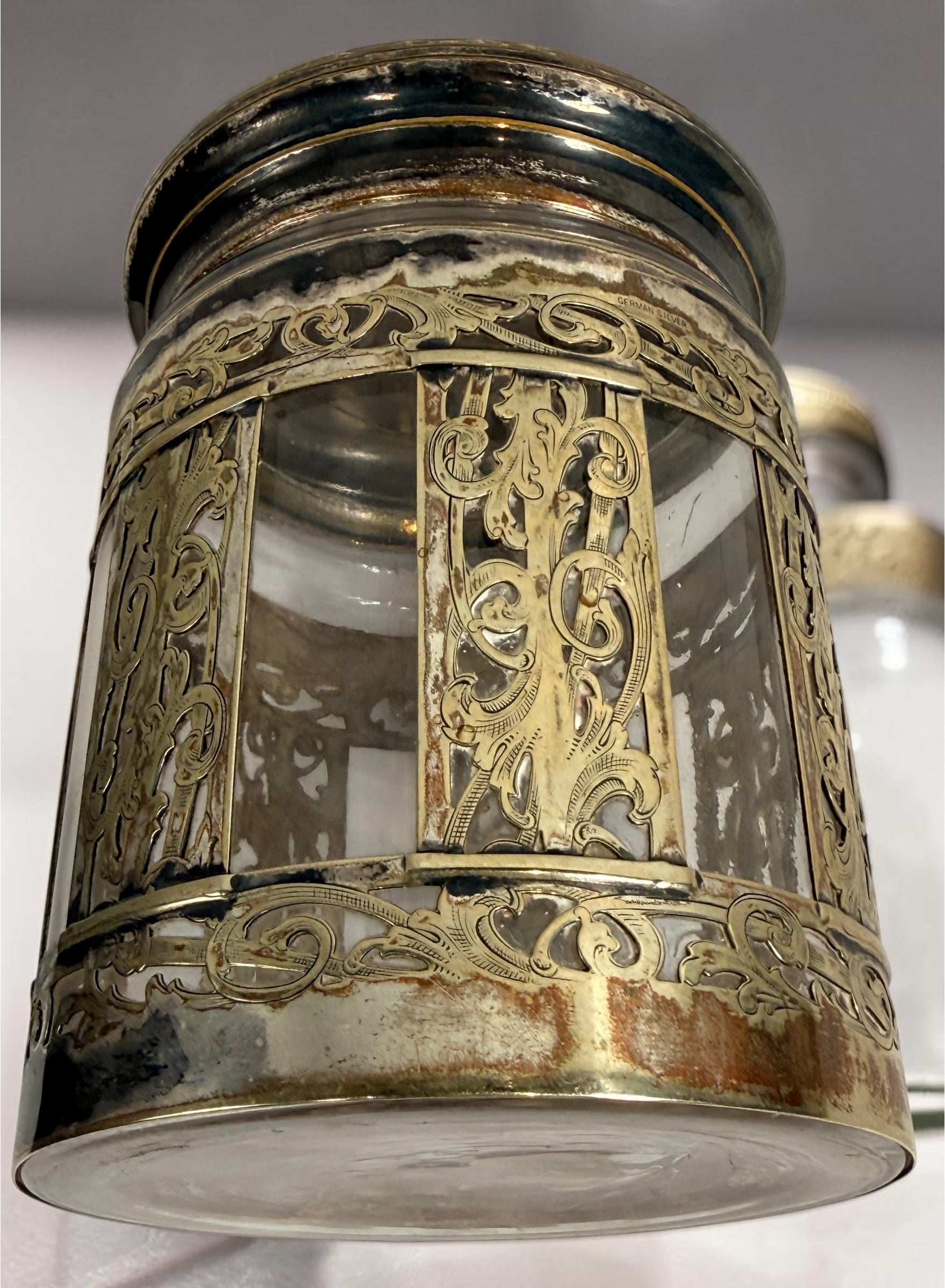 Antique Victorian glass tobacco humidor with ornate German silver overlay, engraved floral motifs, and domed lid. Elegant late-19th-century decorative storage jar.
