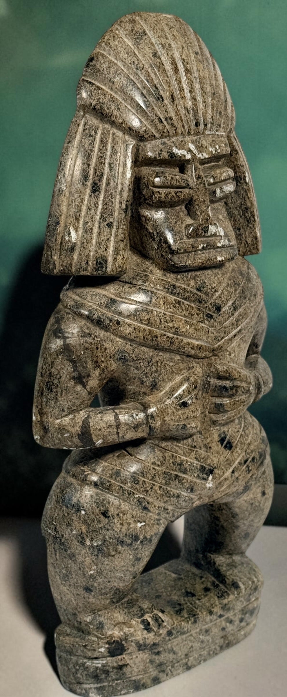 Hand-carved stone warrior figure in Pre-Columbian Mesoamerican style with detailed headdress and geometric features. Unique vintage decorative sculpture.