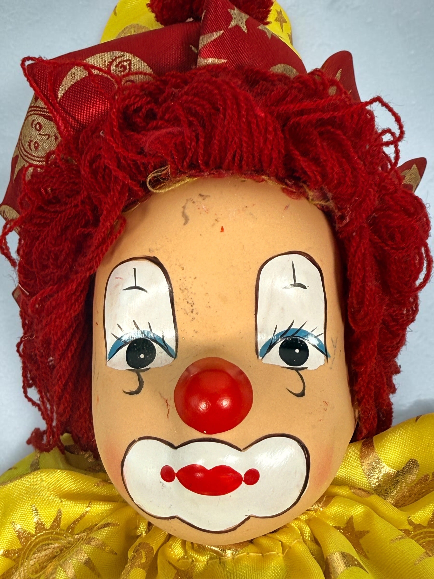 SEO Meta Description: Vintage 12-inch Pierrot clown doll with red and gold celestial costume, yarn hair and painted face. Distinctive collectible circus décor.