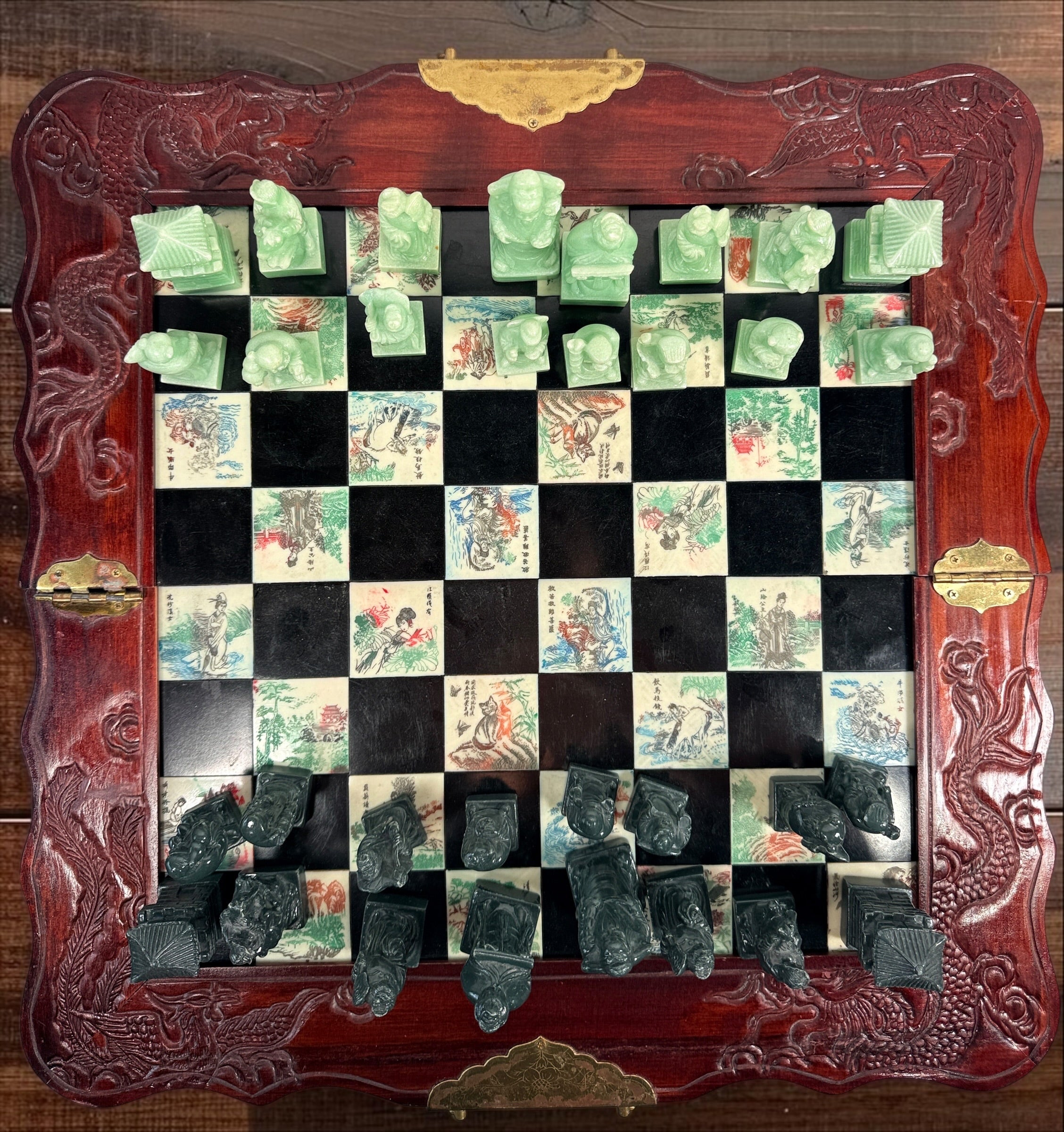Vintage Chinese 32-piece figural chess set with jade-coloured pieces, carved dragon folding wood board, illustrated squares and fitted storage.