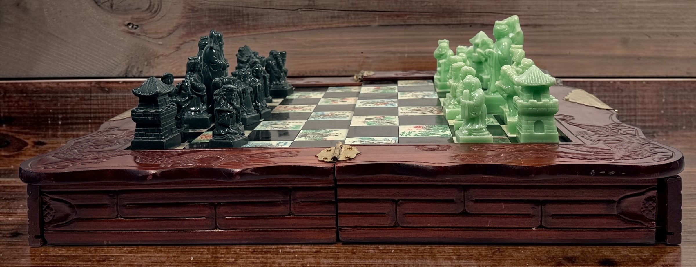 Vintage Chinese 32-piece figural chess set with jade-coloured pieces, carved dragon folding wood board, illustrated squares and fitted storage.