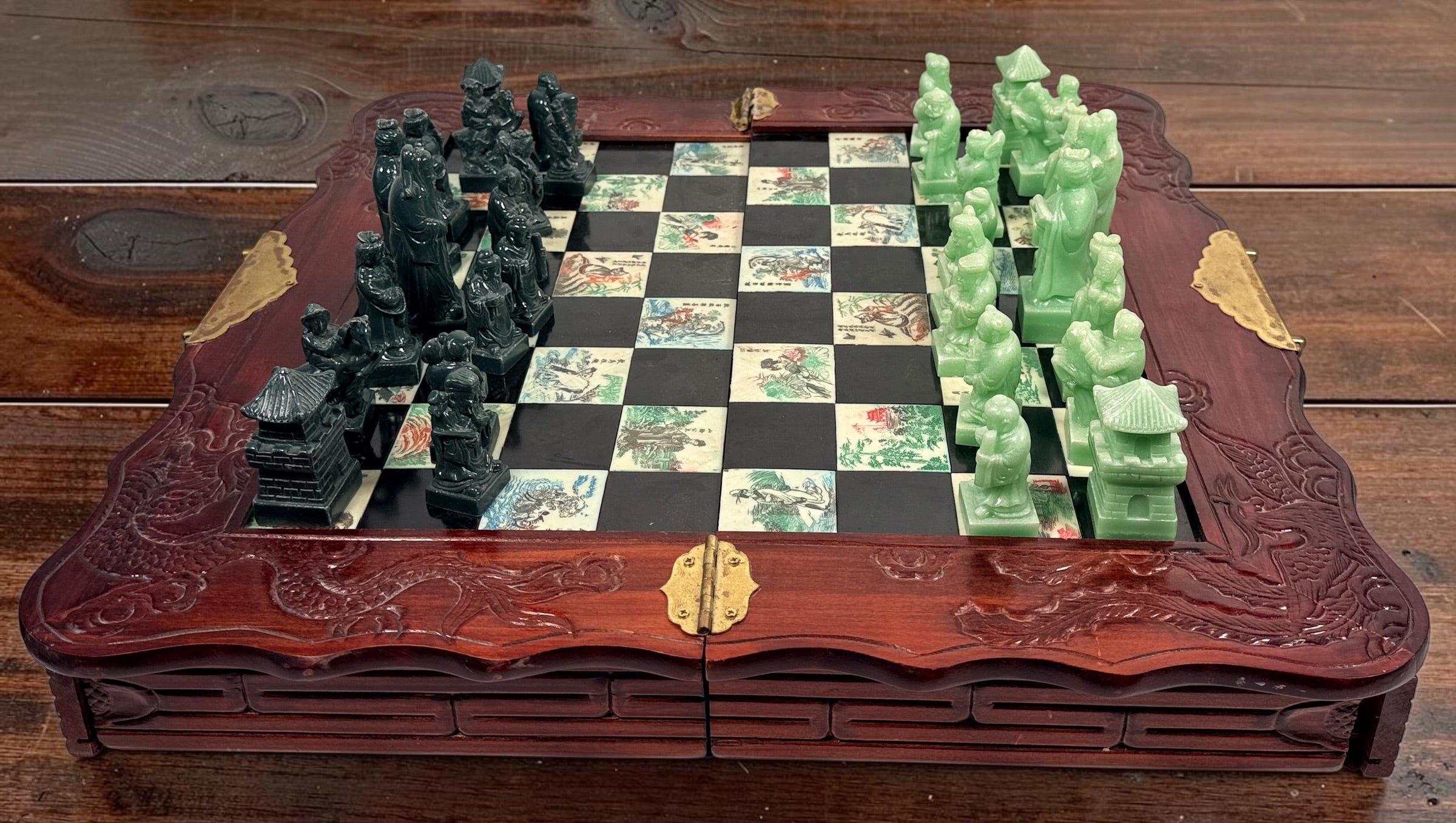 Vintage Chinese 32-piece figural chess set with jade-coloured pieces, carved dragon folding wood board, illustrated squares and fitted storage.
