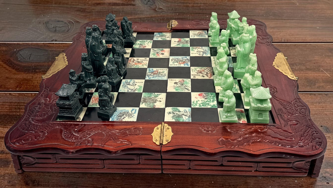 Vintage Chinese 32-piece figural chess set with jade-coloured pieces, carved dragon folding wood board, illustrated squares and fitted storage.