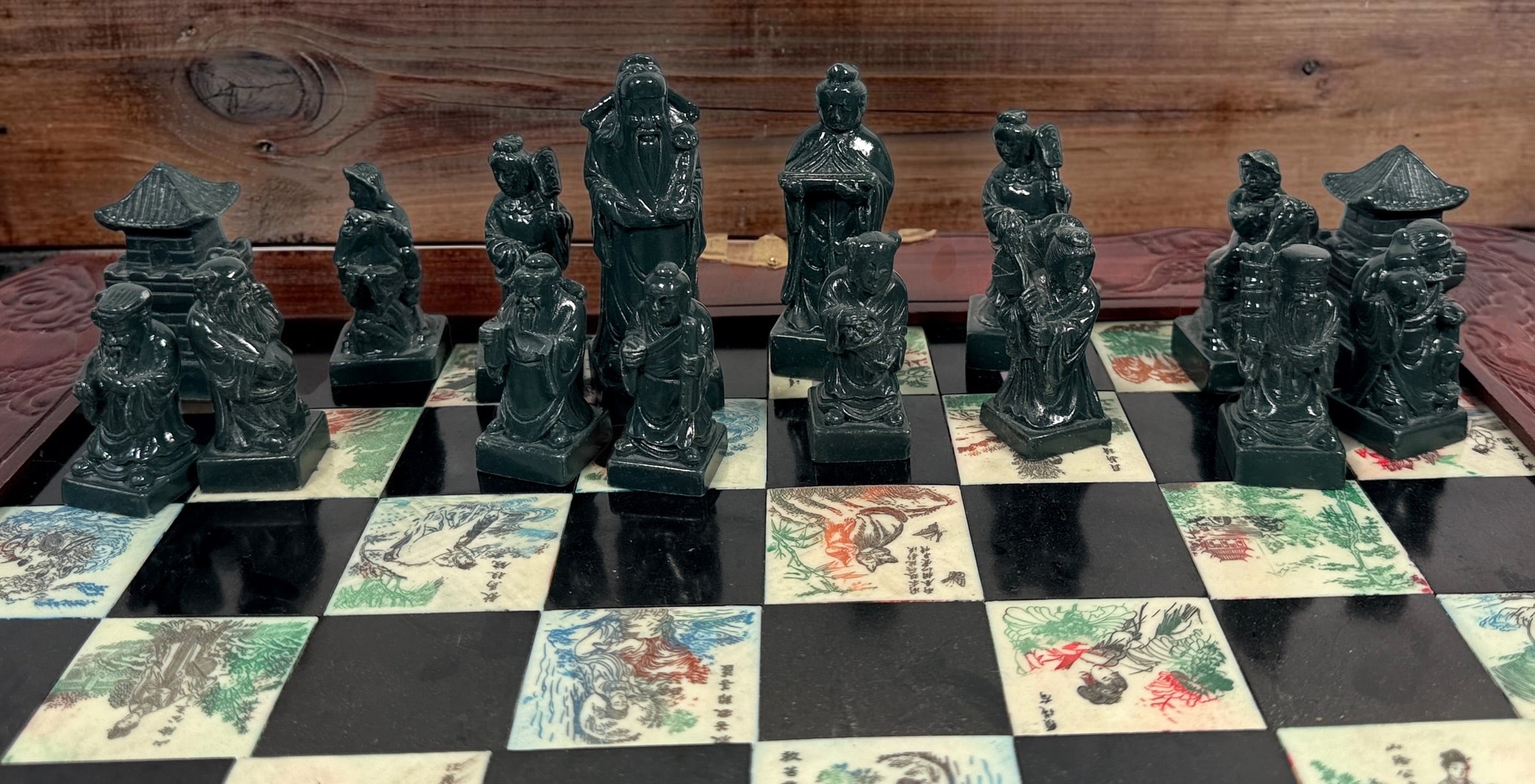 Vintage Chinese 32-piece figural chess set with jade-coloured pieces, carved dragon folding wood board, illustrated squares and fitted storage.