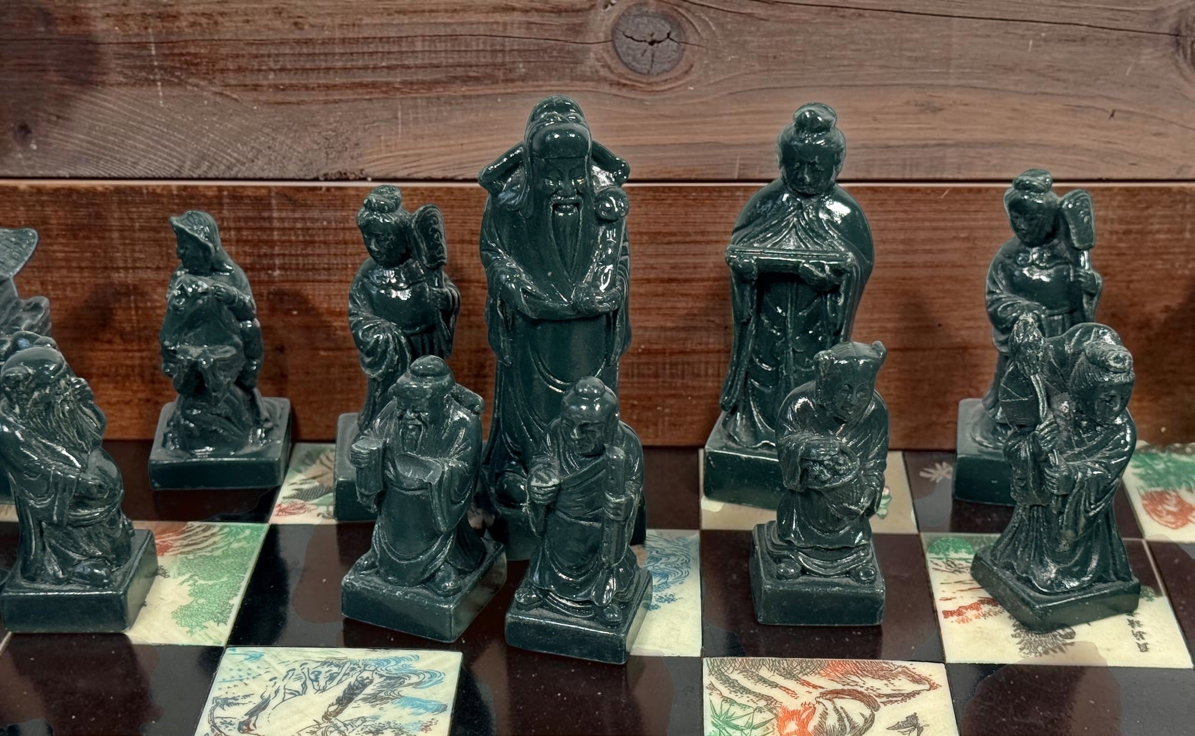 Vintage Chinese 32-piece figural chess set with jade-coloured pieces, carved dragon folding wood board, illustrated squares and fitted storage.