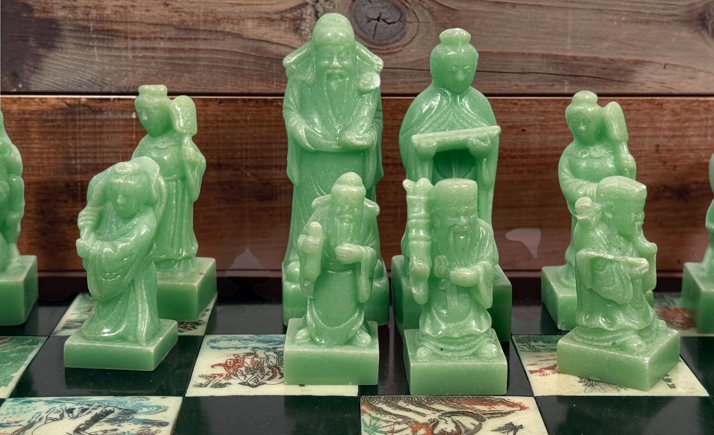 Vintage Chinese 32-piece figural chess set with jade-coloured pieces, carved dragon folding wood board, illustrated squares and fitted storage.