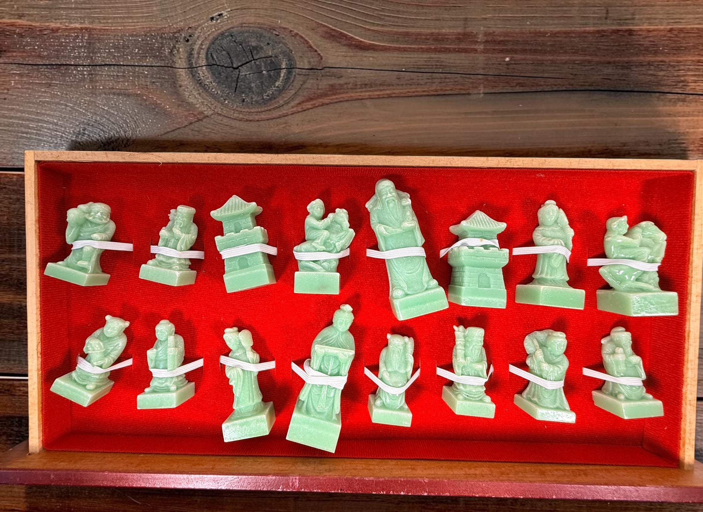 Vintage Chinese 32-piece figural chess set with jade-coloured pieces, carved dragon folding wood board, illustrated squares and fitted storage.