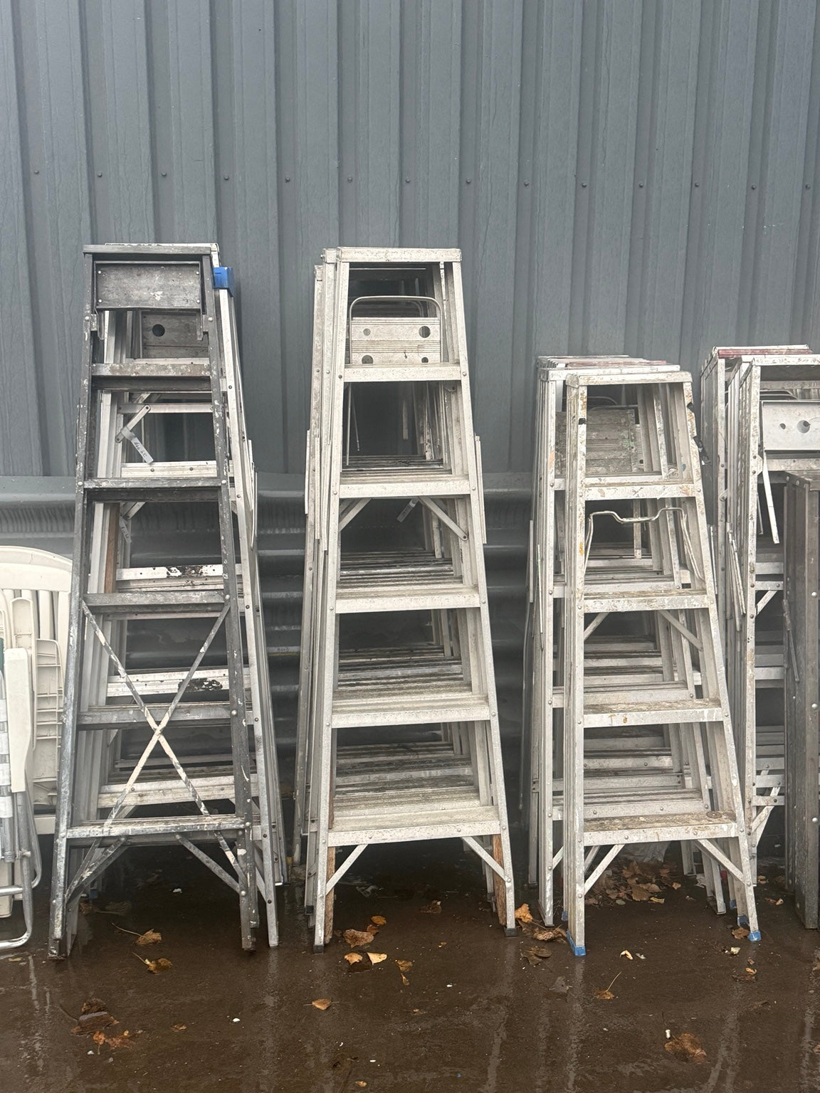 Assorted used aluminum stepladders stacked outside Éco-Dépôt Montréal