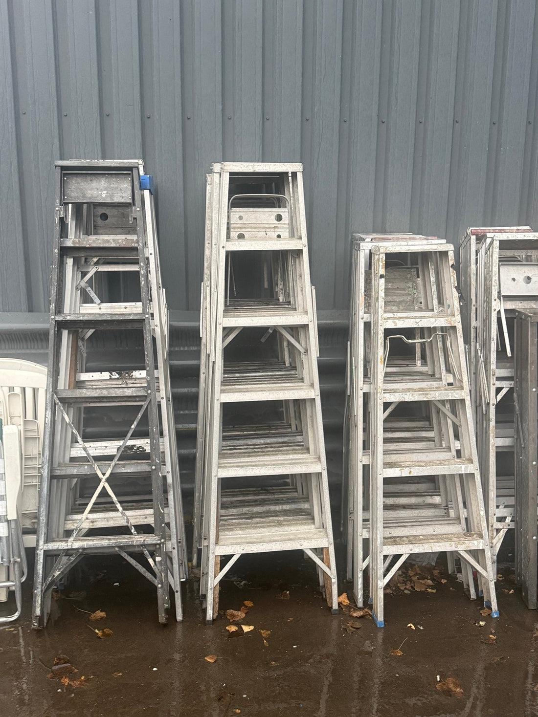Assorted used aluminum stepladders stacked outside Éco-Dépôt Montréal