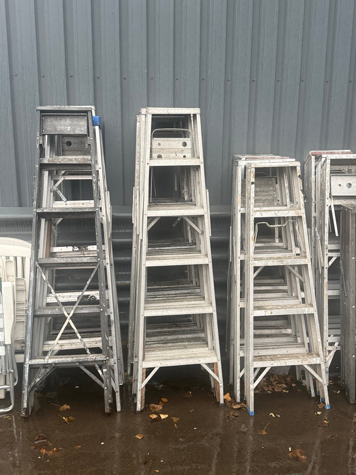 Assorted used aluminum stepladders stacked outside Éco-Dépôt Montréal