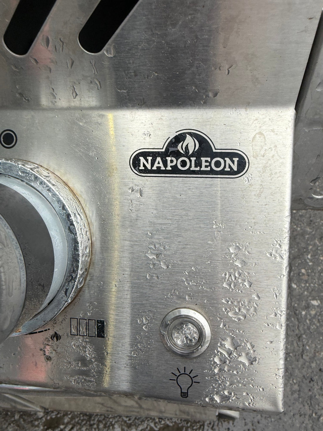 Close-up of Napoleon logo and worn stainless steel control panel