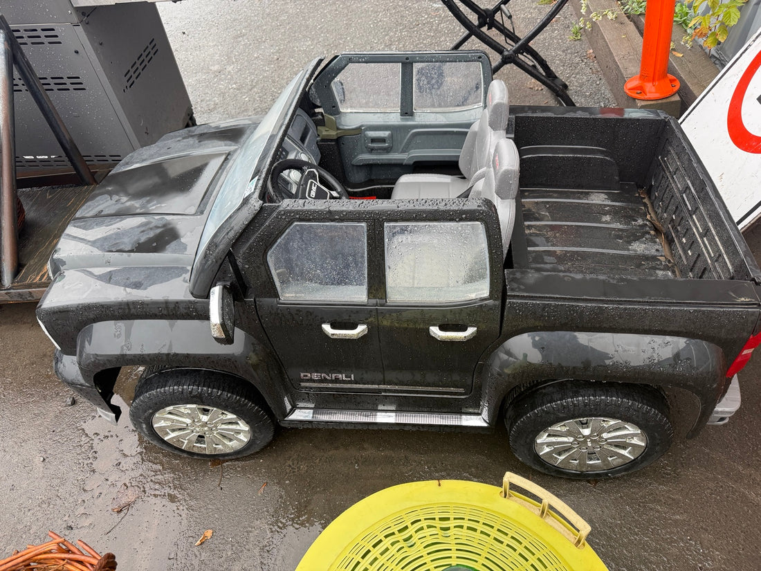 Side view of used GMC Denali ride-on toy truck showing wheels and cargo bed