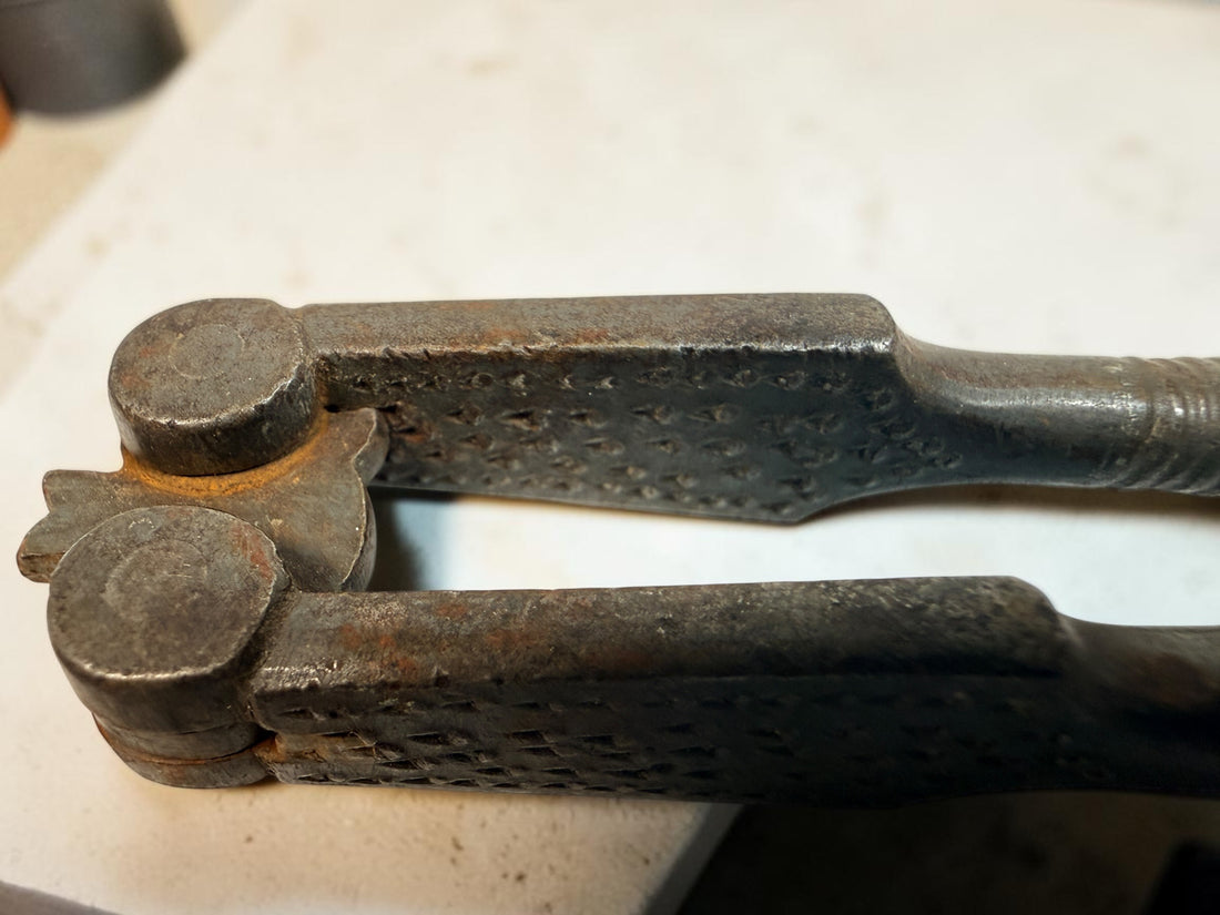 Antique Victorian reversible double nutcracker in iron with decorative handles and textured jaws. Collectible 19th-century kitchen tool.