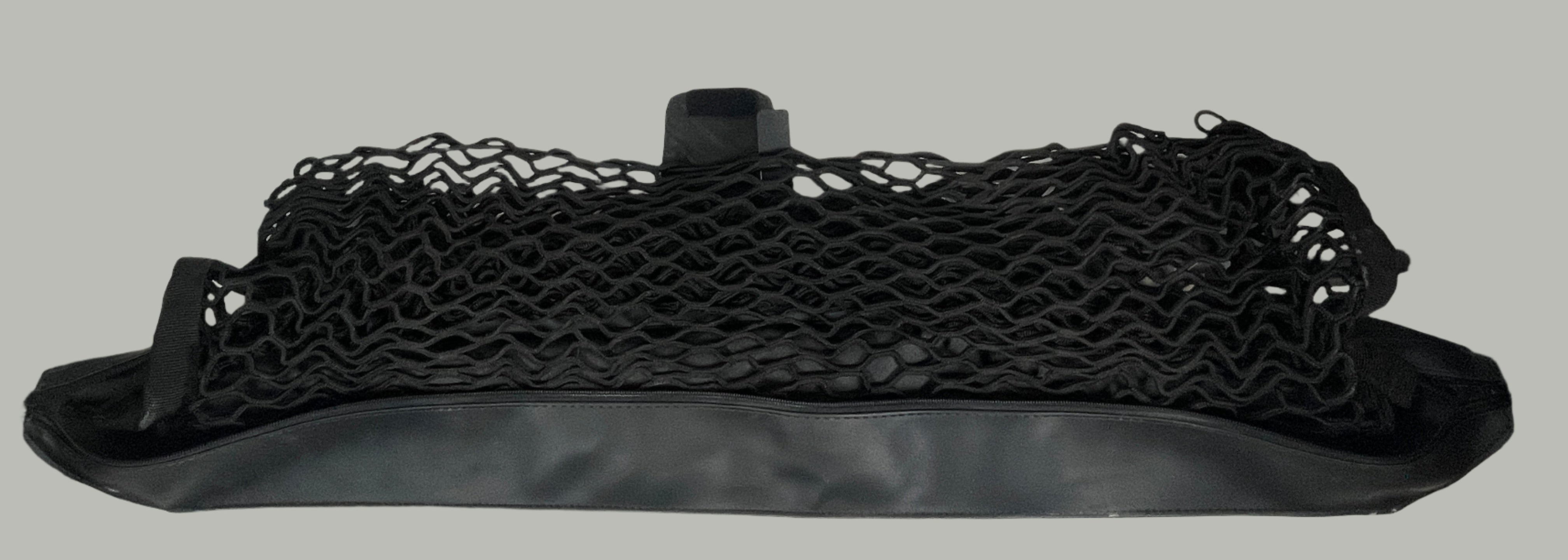 Black mesh bag on a white surface with a white tiled wall background