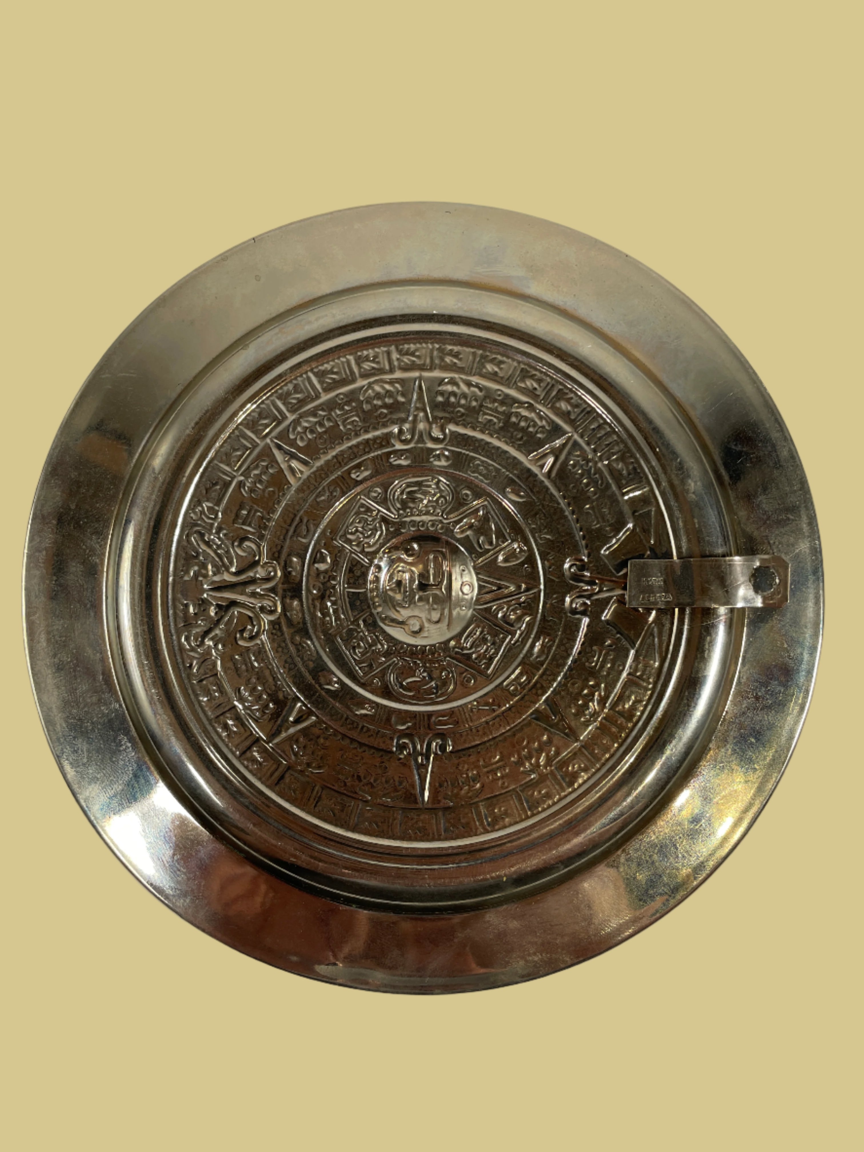 Decorative metal plate with intricate designs on a white background