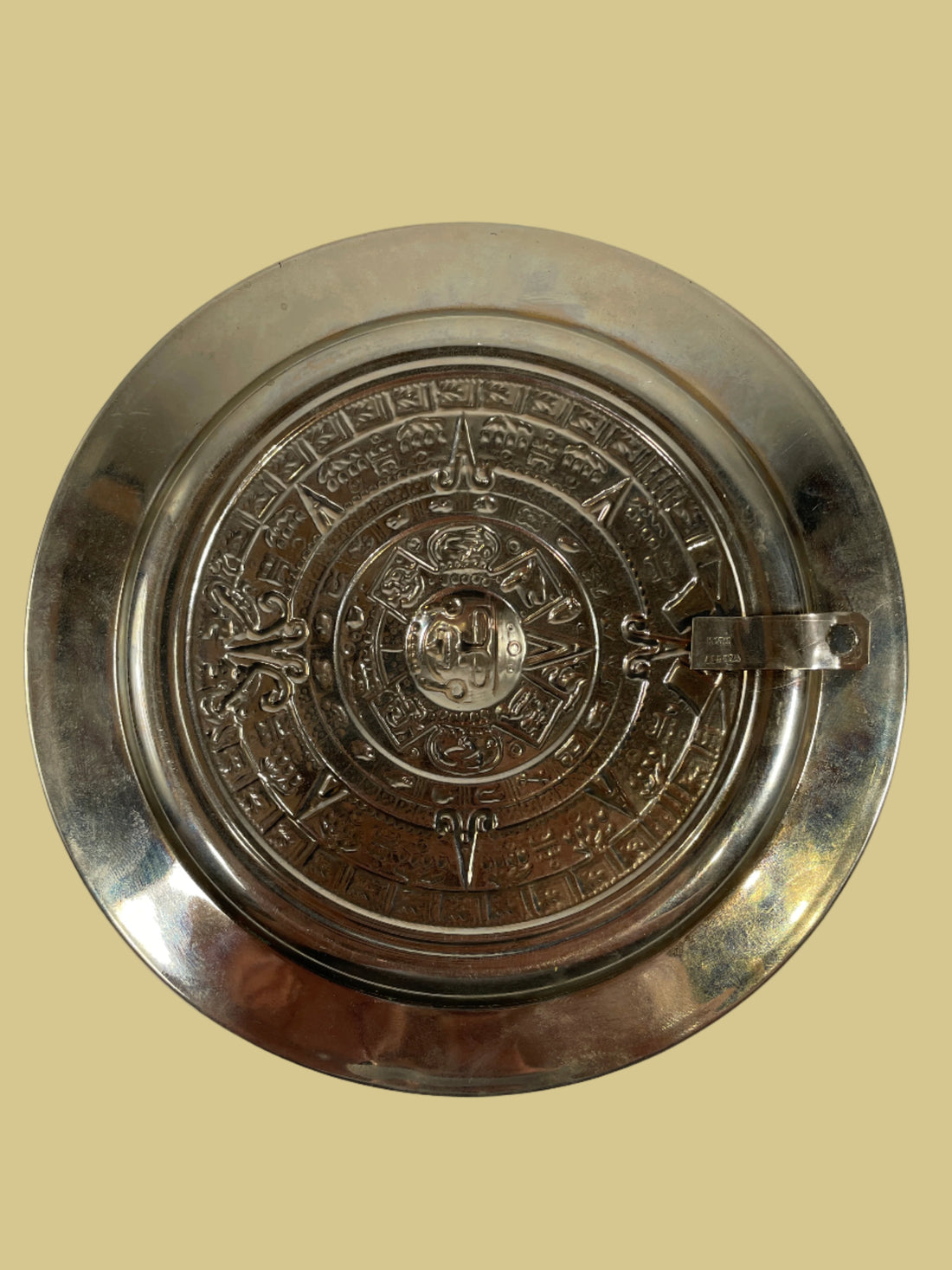 Decorative metal plate with intricate designs on a white background