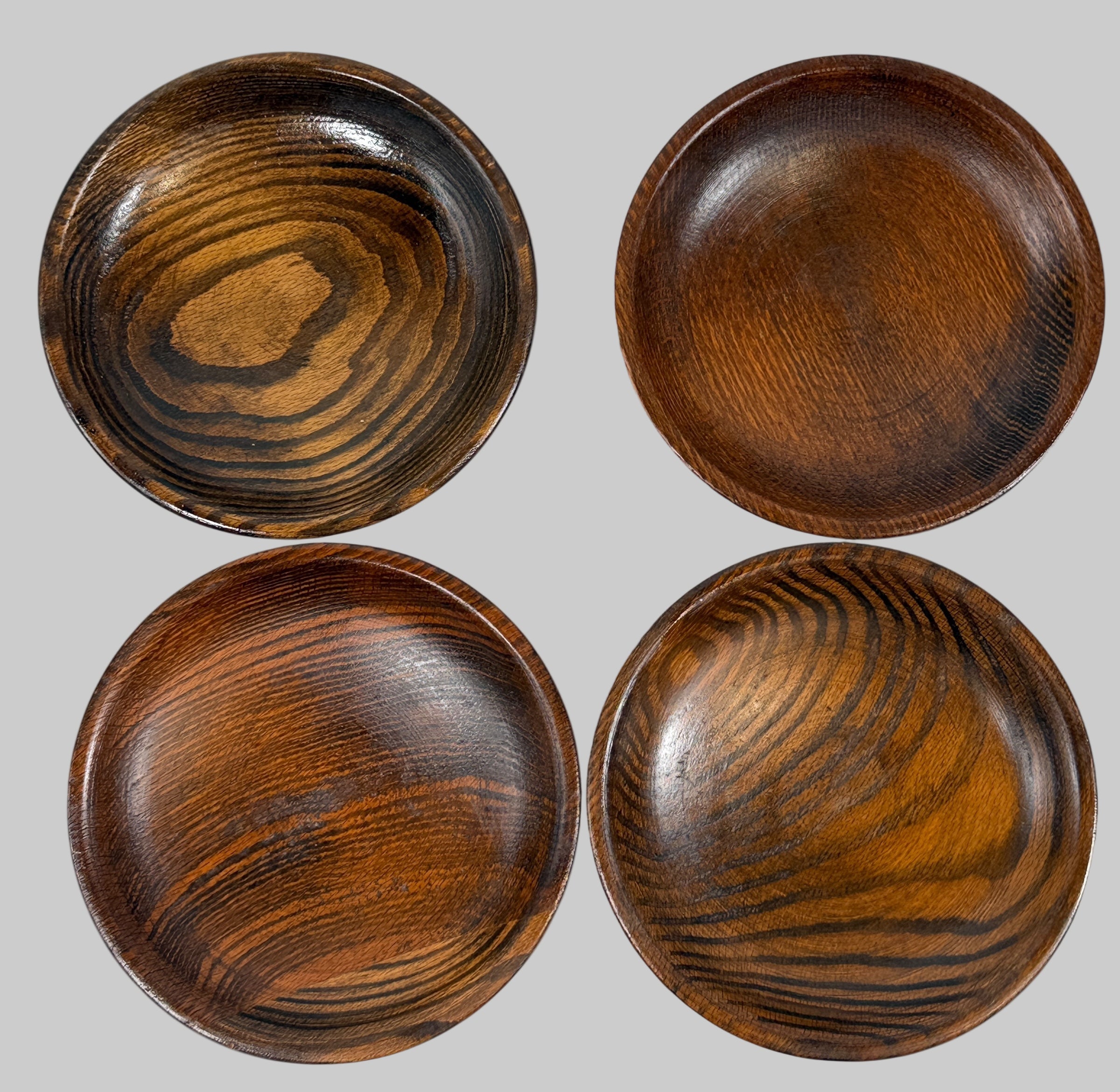 Four wooden bowls with a dark brown finish on a white background
