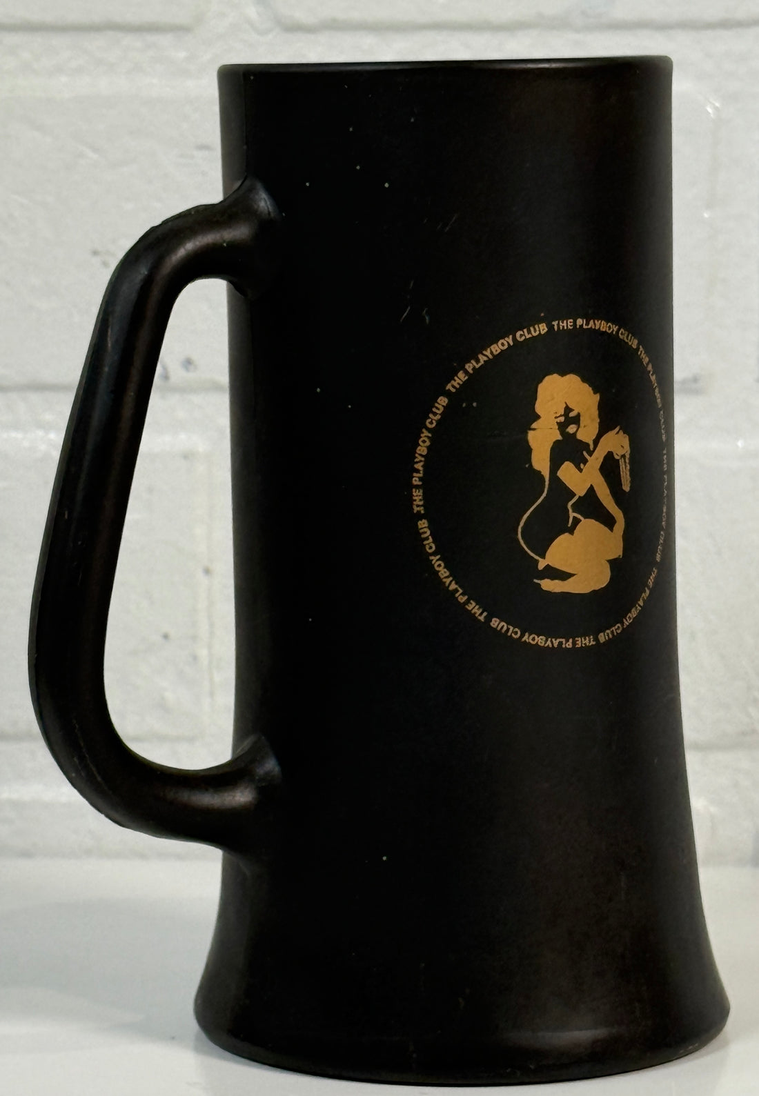 Black mug with gold logo on a light gray background