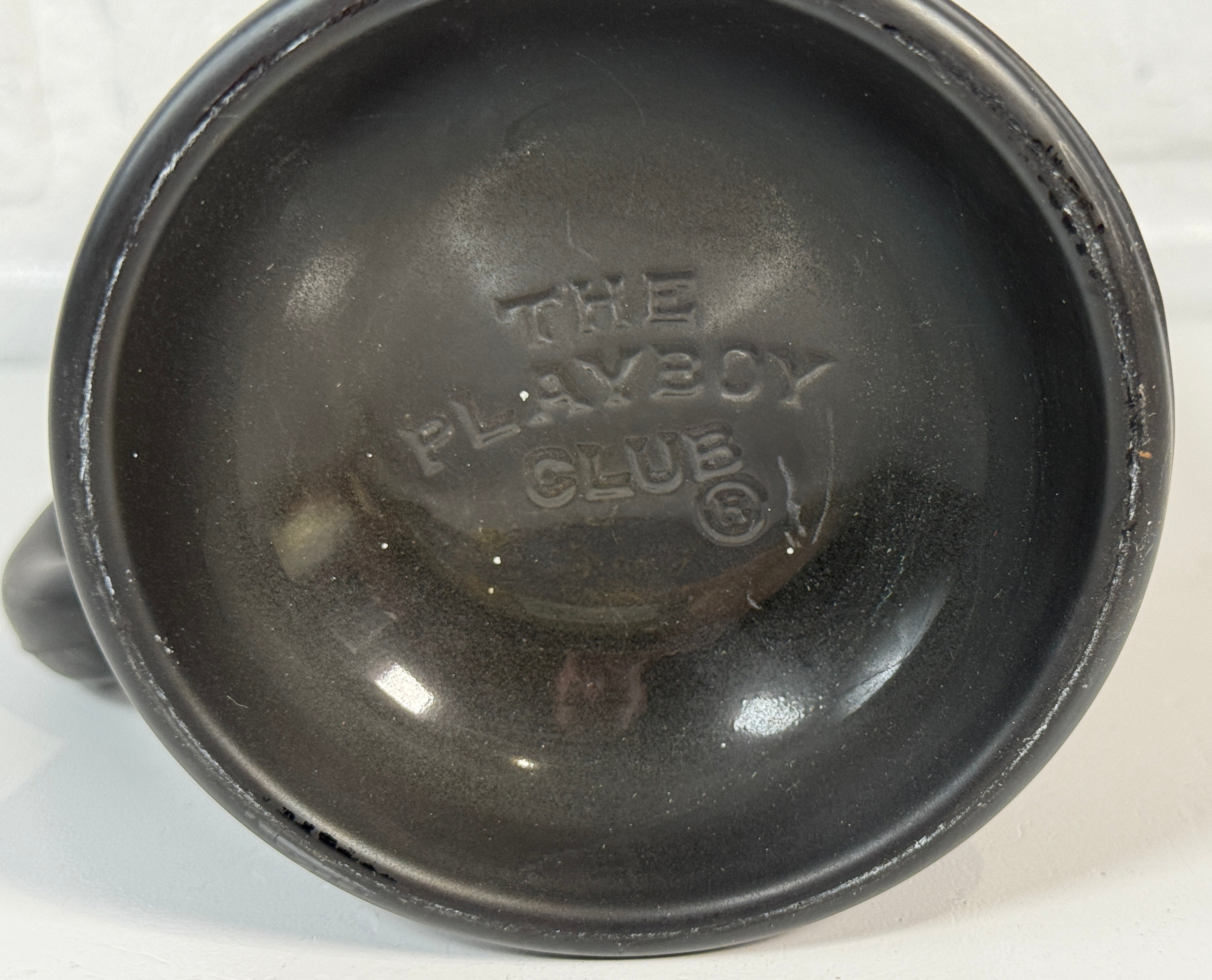 Black plastic component with 'The Playboy Club' branding on a white background