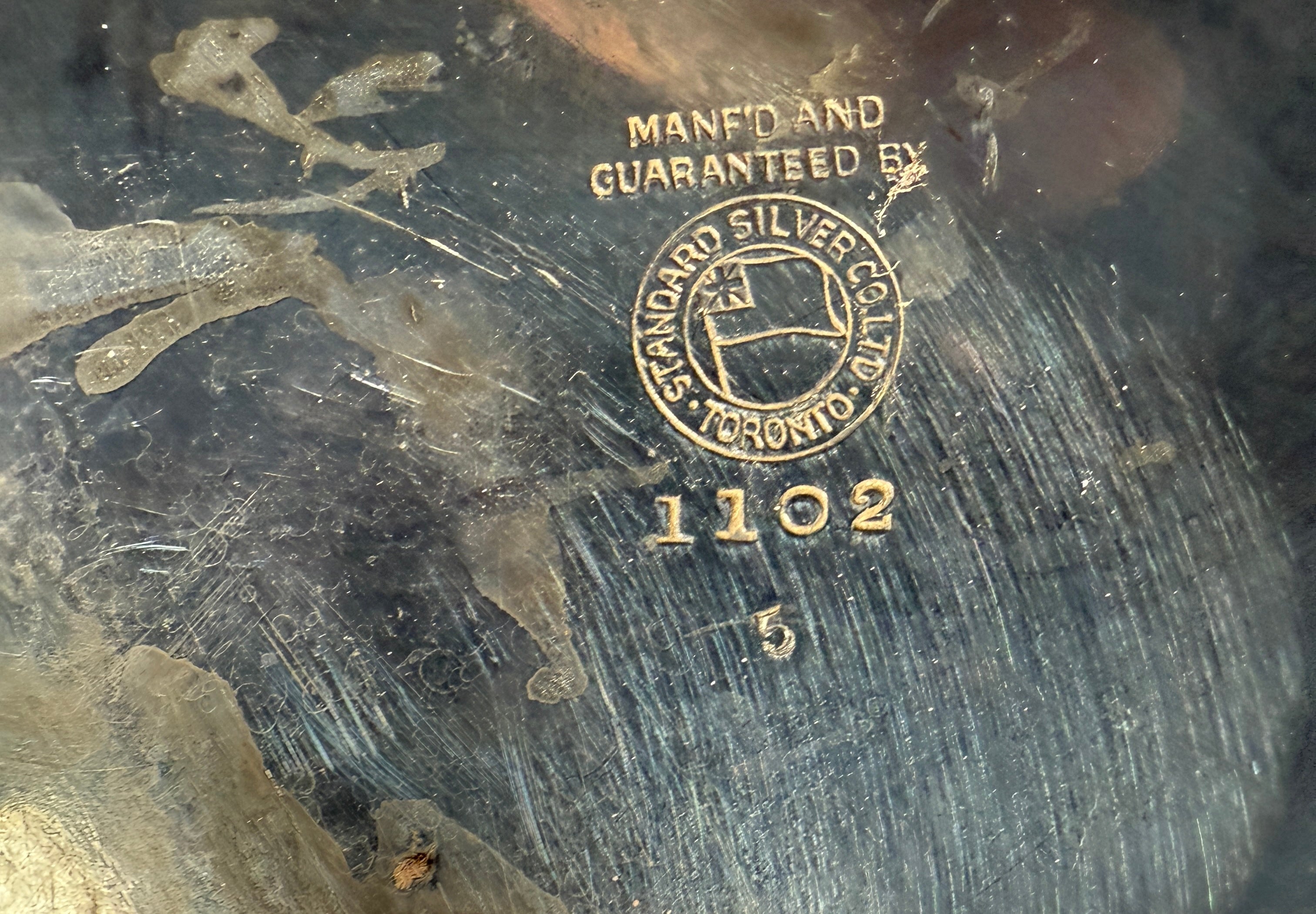 Close-up of a metal surface with 'Standard Silver' branding and number '1102'.
