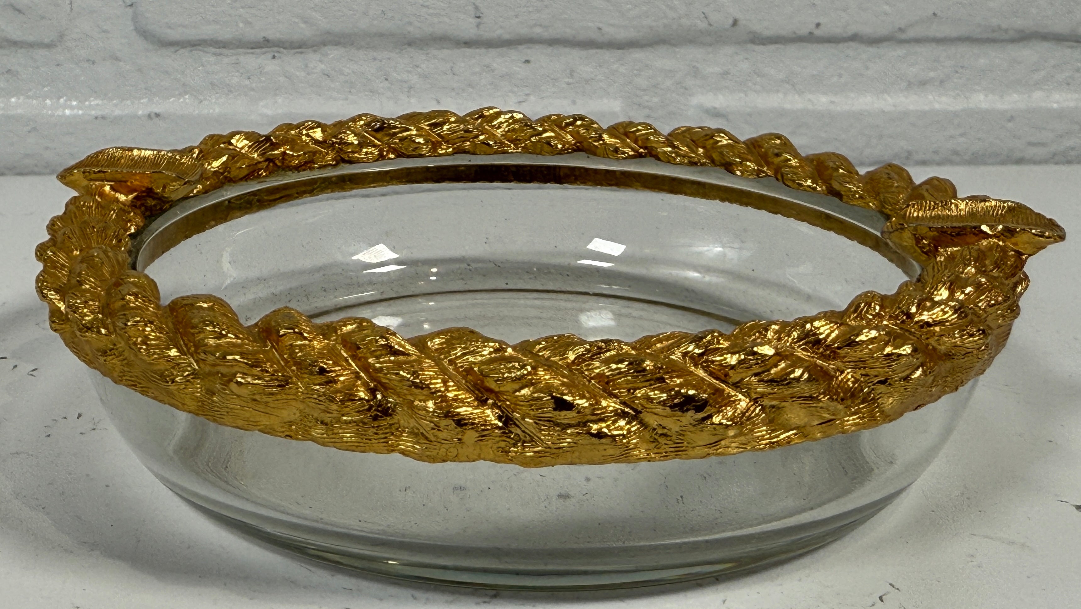 Clear glass bowl with gold decorative rim on a white background