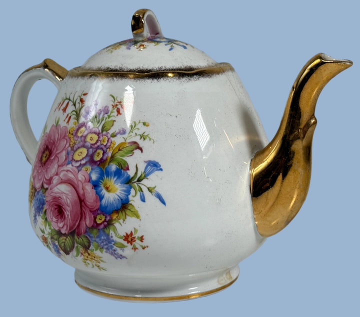 Teapot with floral design and gold accents on a white background