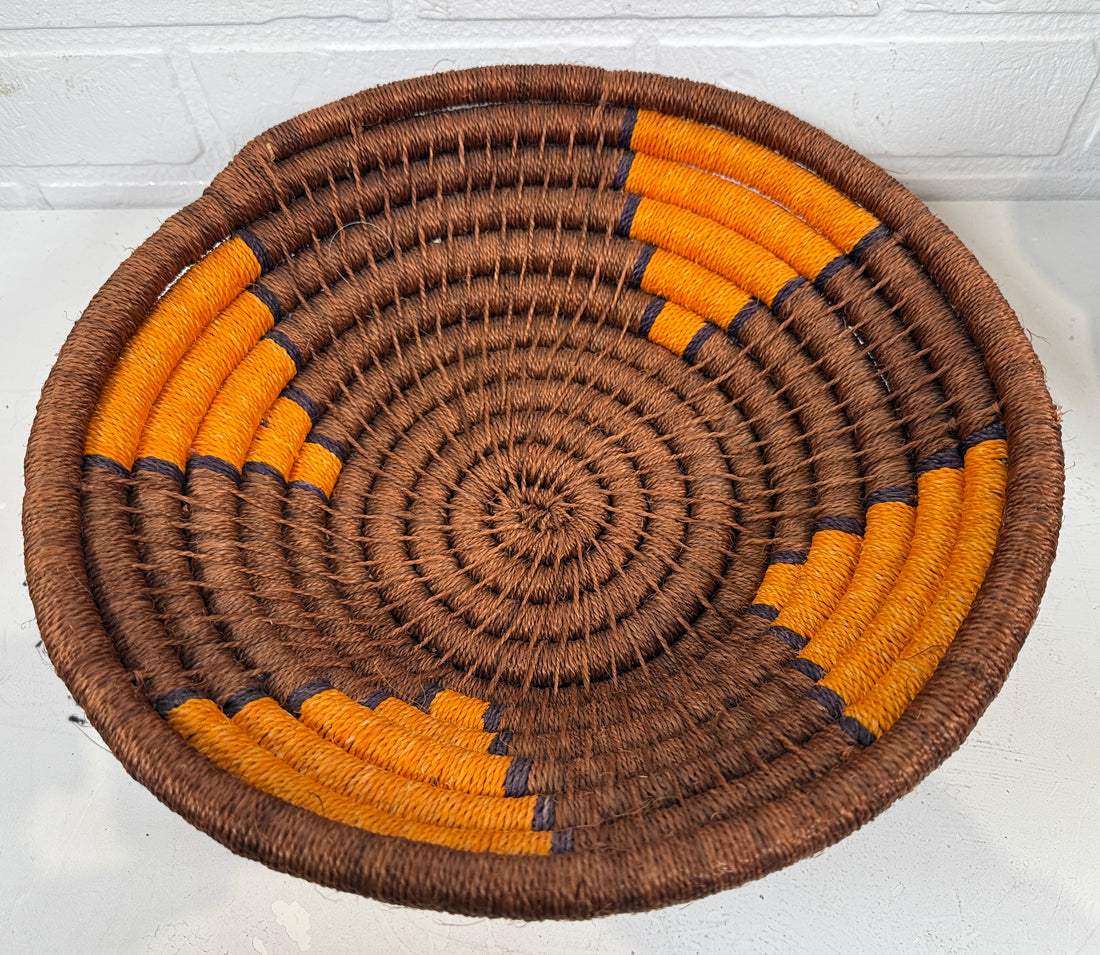 Woven basket with brown and orange pattern on a white surface
